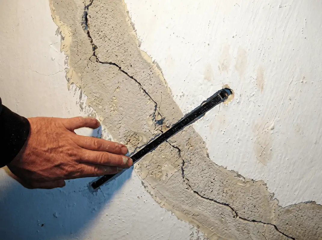 A wall with a large crack is being inspected by a professional in Philadelphia, PA